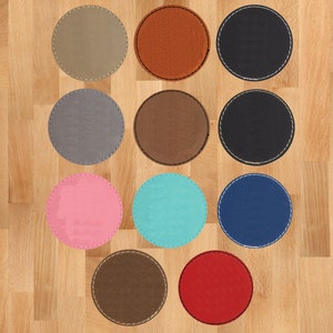 May include: A collection of round coasters in various colors, including tan, orange, black, gray, brown, pink, teal, navy blue, and red. Each coaster has a stitched edge detail, offering a decorative and functional accessory.