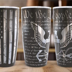 May include: Three stainless steel tumblers with different designs. The first tumbler features a silver and black American flag. The second tumbler features the text "We the People" and a silver eagle with an anchor. The third tumbler features the text "We the People" and a silver eagle with an anchor.