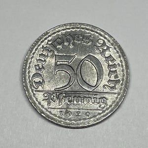 Può includere: Una moneta color argento del Reich tedesco, con il numero "50" in evidenza. La moneta è iscritta con testo tedesco e l'anno "1920". La moneta ha una forma circolare con un bordo dettagliato.