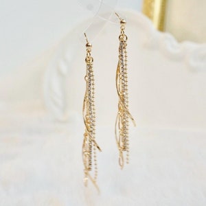 May include: Gold dangle earrings with multiple strands of small, clear crystals.