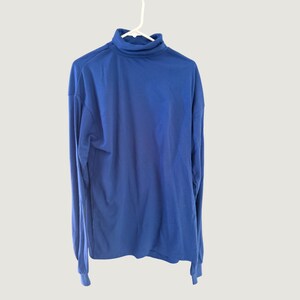 May include: A solid royal blue long-sleeve shirt featuring a high turtleneck collar. The garment is constructed with a smooth, uniform fabric and is displayed hanging on a white plastic hanger, showcasing a simple, clean design with long sleeves.