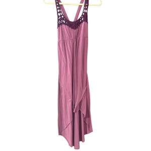 May include: A mauve-colored dress with a flowing, asymmetrical hemline. The dress features a scoop neckline with a dark purple crocheted trim and straps. The dress is hanging on a beige hanger against a white background.