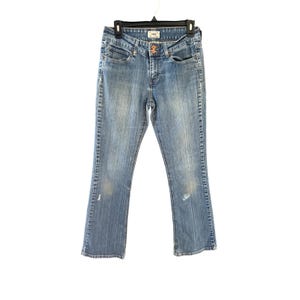 May include: Light blue denim jeans featuring a faded wash, a mid-rise waist with a double button closure, five pockets, and subtle whiskering details. The jeans have a straight leg cut with light distressing on the thighs and lower legs.