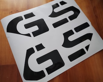 Könnte beinhalten: Schwarze Vinyl-Aufkleber mit geometrischem Design. Die Aufkleber sind pfeilförmig und haben einen schlichten, modernen Look.