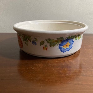 Könnte beinhalten: Eine weiße Keramikschüssel mit Blumenmuster. Die Schüssel hat ein blaues, gelbes und rotes Blumenmuster am Rand.