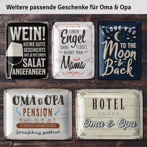 Pu&ograve; includere: Una collezione di insegne in metallo in stile vintage con varie citazioni e disegni. Un'insegna dice "WEIN!" con una grafica di calice. Un'altra dice "I LOVE YOU TO THE MOON & BACK." Altre insegne includono "OMA & OPA" e "HOTEL."