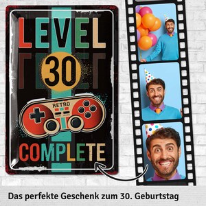 May include: A black metal sign with the words "LEVEL 30 COMPLETE" in colorful letters. A retro video game controller graphic is below the number 30. The sign is accompanied by a film strip with three photos of a man celebrating.