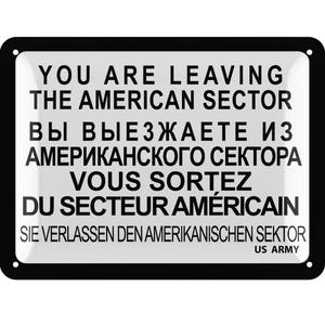 Könnte beinhalten: Ein rechteckiges Metallschild mit abgerundeten Ecken und schwarzem Rand. Auf dem Schild steht der Text "YOU ARE LEAVING THE AMERICAN SECTOR" auf Englisch, sowie Übersetzungen auf Russisch, Französisch und Deutsch. Unten steht "US ARMY".