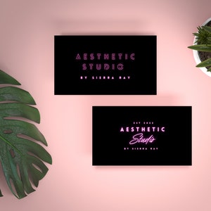 May include: Two black business cards with white text. The top card reads "Aesthetic Studio by Sierra Ray". The bottom card reads "Est. 2022 Aesthetic Studio by Sierra Ray". The text "Studio" is in pink neon.
