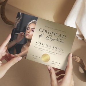 Puede incluir: Un certificado de finalización dorado con borde negro y el texto "THE BEAUTY STUDIO PRESENTS CERTIFICATE of Completion JULIANA SILVA For completing the ultimate makeup mastery training course DATE INSTRUCTOR". Una foto de una mujer que se maquilla está en la esquina superior izquierda.