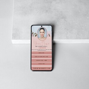 May include: A pink and white mobile phone screen displaying a business card with a woman's headshot, the text "Your Name", and social media handles. The card also includes the text "Book Now", "Gift Card", "Gift My Skill", and "Contact Me". The bottom of the screen displays the text "www.website.com".