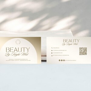 May include: A gold and white business card with the text "BEAUTY by Kayla West" and contact information. The card also includes a QR code.