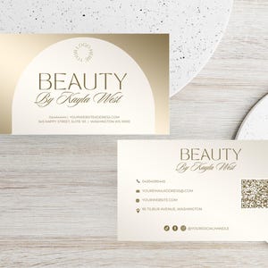 May include: Gold and white business card with the text "BEAUTY By Kayla West" and contact information. The back of the card has a QR code and social media icons.