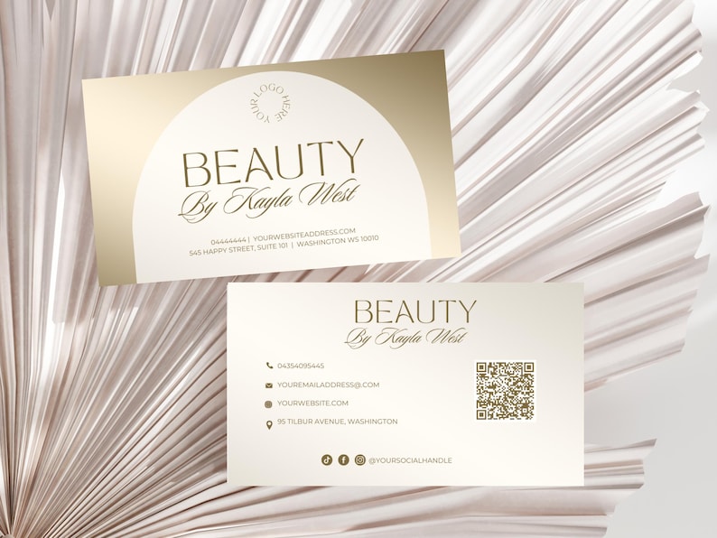 May include: A white business card with gold text and a gold circle logo. The text reads "BEAUTY By Kayla West" and includes contact information such as a phone number, email address, website, and social media handle. The card also features a QR code.