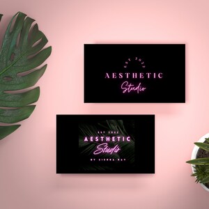 May include: Two black business cards with white text. The top card says "EST 2023 AESTHETIC Studio" in a circle. The bottom card says "EST 2023 AESTHETIC Studio BY SIERRA RAY" with a green tropical leaf background.