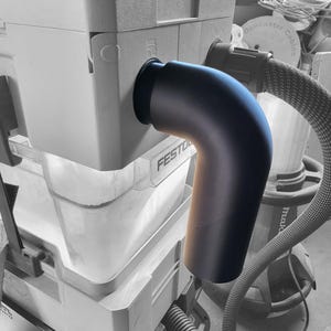 Puede incluir: Un adaptador de manguera de recolección de polvo de plástico negro con una curva de 90 grados se conecta a un contenedor de recolección de polvo gris etiquetado como "FESTO"