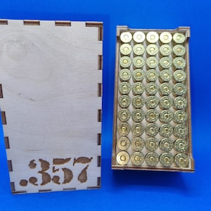 May include: A wooden box with a label that says "357" and is filled with gold-colored bullets.