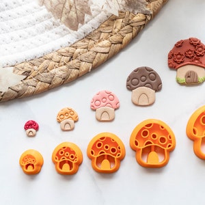 Peut inclure: Un ensemble de neuf emporte-pièces en forme de champignon de différentes tailles. Les emporte-pièces sont en plastique orange et présentent une variété de motifs, notamment des pois, une maison et une simple forme de champignon.