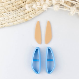 May include: Two pairs of earrings, one pair is light brown and the other pair is light blue. The earrings are shaped like a teardrop.
