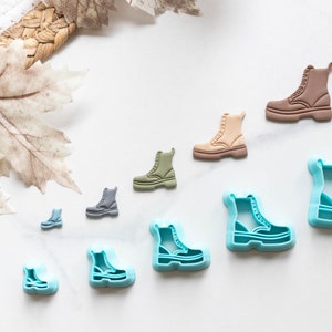 May include: A set of nine different sized cookie cutters shaped like boots. The cutters are made of blue plastic and are arranged in a row from largest to smallest.