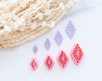 Könnte beinhalten: Ein Satz mit sieben rautenförmigen Ausstechern, vier sind rosa und drei sind lila. Die Ausstecher haben ein florales Design.