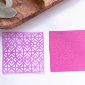 May include: Two purple plastic stencils with geometric patterns. The stencil on the left is translucent and the stencil on the right is opaque.