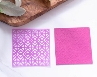 Puede incluir: Dos plantillas de plástico morado con patrones geométricos. La plantilla de la izquierda es translúcida y la plantilla de la derecha es opaca.