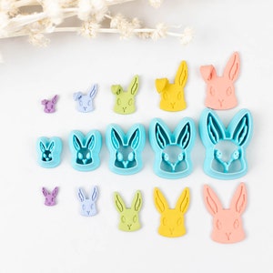 May include: A set of 12 blue, green, yellow, and pink bunny cookie cutters of varying sizes. The cutters are arranged in rows on a white surface.