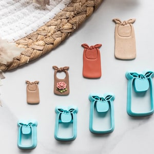 Può includere: Un set di sette stampini per biscotti di diverse dimensioni e colori. Gli stampini hanno la forma di bavaglini con un fiocco in cima. Gli stampini sono in plastica e sono perfetti per fare biscotti o pasta di zucchero.
