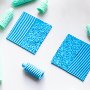 May include: Two blue textured squares with a striped pattern on one side and a smiley face pattern on the other side.  There are several light blue and green rollers with smiley face patterns.