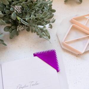 May include: A purple corner bookmark with a white stitched border is placed on a book open to a page titled "Chapter Twelve".