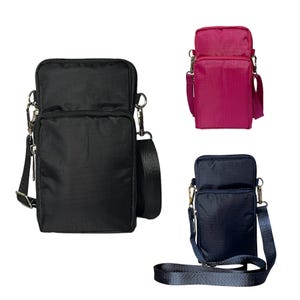 May include: Three different coloured crossbody phone bags. The bags are made of a nylon fabric and have a zippered closure. The bags are available in black, pink, and navy blue.