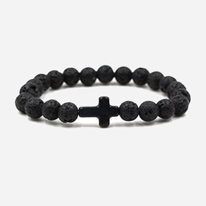 May include: Black lava rock beaded bracelet with a black cross charm.