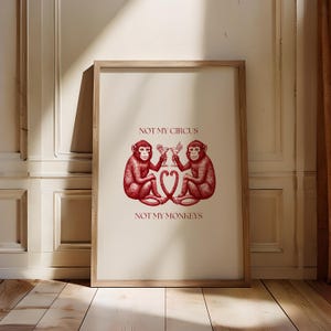 May include: A framed print with a red illustration of two monkeys holding cocktails. The text "Not my circus, not my monkeys" is printed below the monkeys.