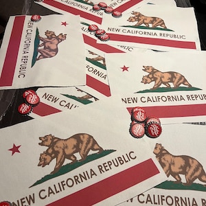 以下が含まれることがあります： 茶色のクマのイラストと赤いアクセントが特徴の「ニューカリフォルニア共和国」の旗がいくつか表示されています。「Nuka Cola」の文字が入った赤と白のボトルキャップが散らばっています。旗には赤いストライプとテキストがあります。