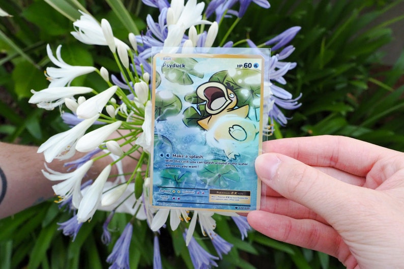 May include: A Pokemon trading card featuring Psyduck with a gold border. The card is a basic card with a HP of 60. The card has an illustration of Psyduck in the water with lily pads. The card text reads 'Make a splash' and 'While this card is on the field, you can splash around in the water whenever you want!'.