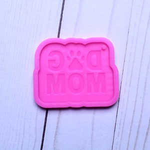 May include: Pink silicone mold with the words "Dog Mom" and a paw print in the center.