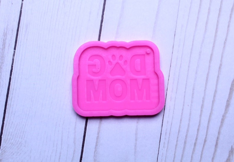 May include: Pink silicone mold with the words "Dog Mom" and a paw print in the center.
