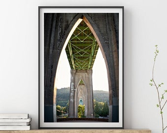 May include: Framed photograph of a bridge's arched supports, viewed from below. The bridge's concrete structure is gray, with green crossbeams visible. The photograph is displayed on a wooden shelf with books and a glass vase with a plant.