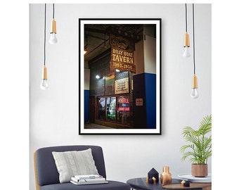 May include: Framed print of the Billy Goat Tavern, established in 1934, with a brick facade and neon sign. The image is displayed in a living room setting with a modern chair, side table, and decorative lighting.