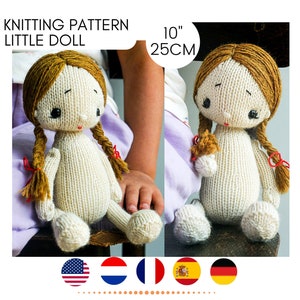 May include: Knitting pattern for a 10-inch (25 cm) little doll. The doll is made of white yarn with brown hair and red bows. The doll is sitting on a wooden chair.