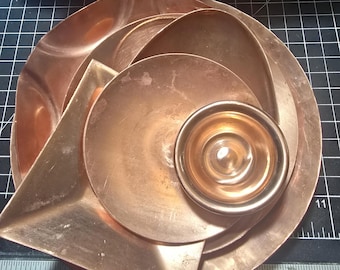 May include: A set of five copper bowls, nested together, with a shiny, metallic finish. The bowls are arranged in a circular pattern, with the smallest bowl in the centre.
