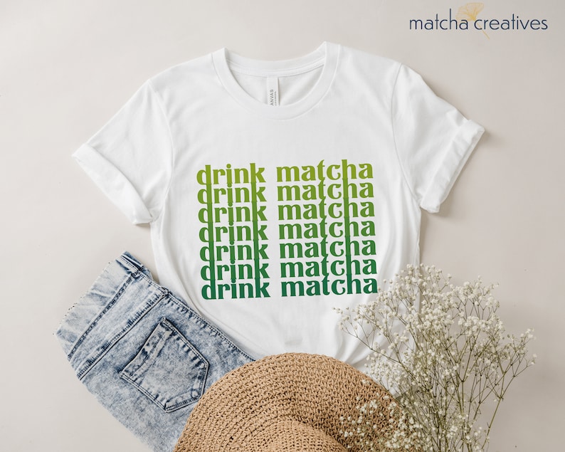 May include: White t-shirt with the text "drink matcha" repeated in a gradient of green and yellow.