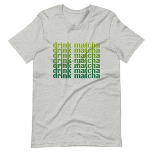 May include: A heather grey t-shirt with the text "drink matcha" repeated six times in a gradient of green and yellow.