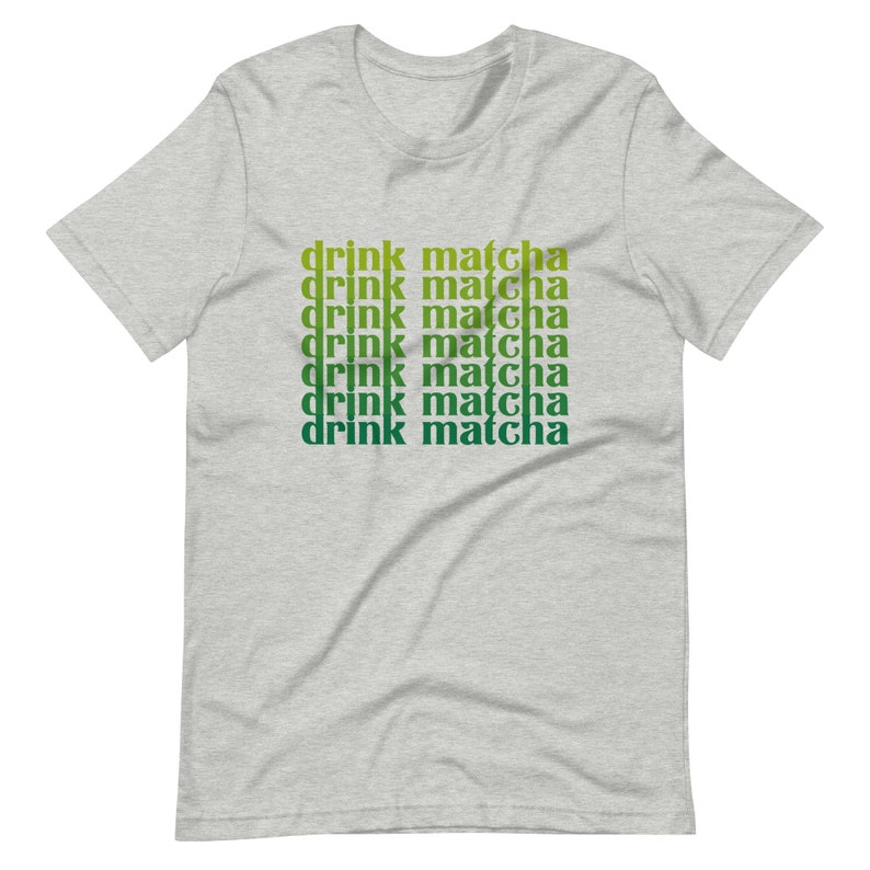 May include: A heather grey t-shirt with the text "drink matcha" repeated six times in a gradient of green and yellow.