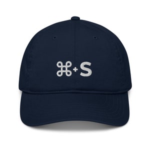 May include: A navy blue baseball cap with a white embroidered command key and the letter 'S' on the front.