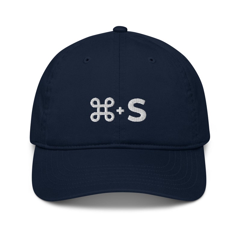 May include: A navy blue baseball cap with a white embroidered command key and the letter 'S' on the front.