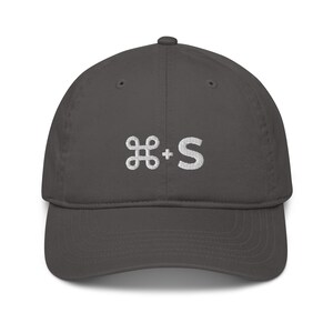 May include: A dark gray baseball cap with a white embroidered command key and the letter 'S' on the front.