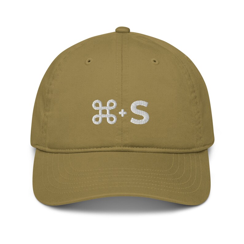 May include: A khaki colored baseball cap with a white embroidered command key and the letter "S" on the front.
