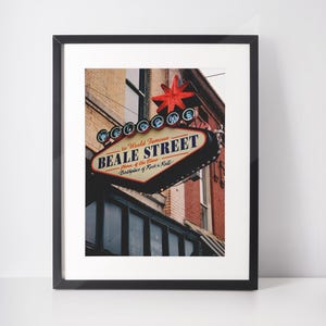 Pode incluir: Uma placa de néon com uma estrela vermelha no topo, anunciando "Bem-vindo à mundialmente famosa Beale Street, lar do blues, berço do rock 'n' roll".